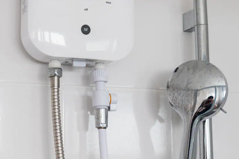 A close-up of a shower setup shows a white water heater, metal hose, connecting valve, and a chrome showerhead mounted on a tiled bathroom wall—typical work by a professional plumber in Brevard County, FL.